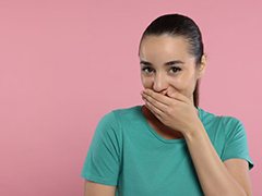 Woman in green t-shirt covering her mouth