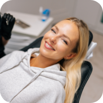 Blonde woman smiling and leaning back in dental chair