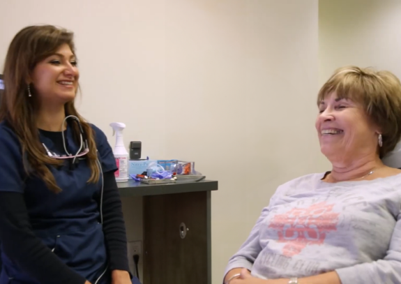 Woman in dental chair laughing with her dentist