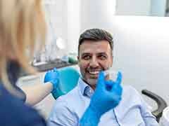 A young dentist showing an Invisalign aligner to her patient