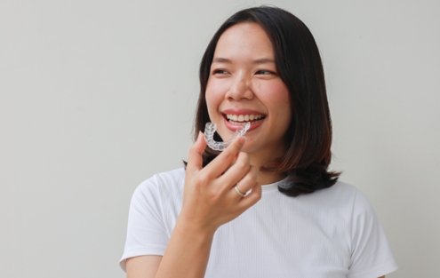 een girl smiling while holding clear aligner