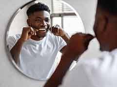 Man smiling at reflection while flossing