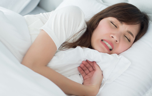 Woman sleeping in bed while grinding her teeth