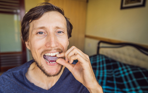 Man sitting on bed putting in nightguard