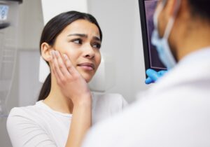 a dental patient holding her mouth in pain