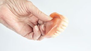 Senior’s hand holding upper denture