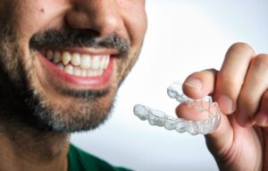 Man holding Invisalign aligner close to his mouth